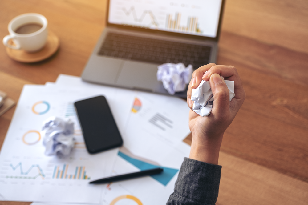 Frustrated person crumpling paper at work desk