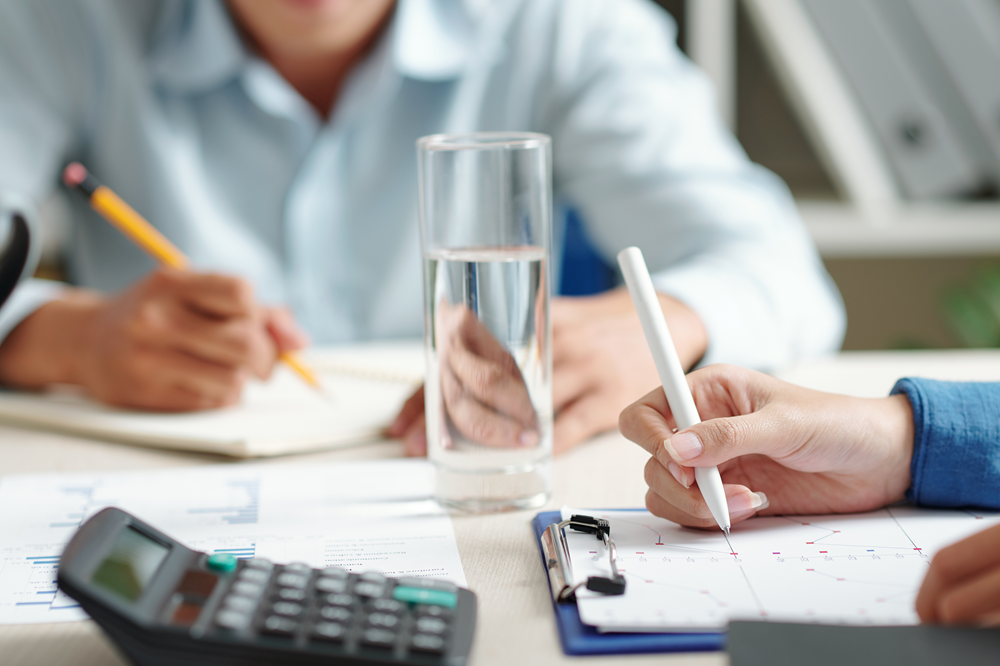 Business meeting with people writing and calculating